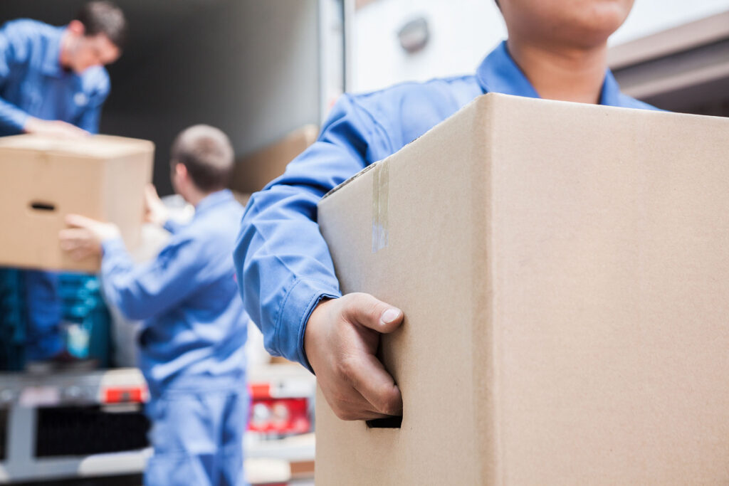 Team members in blue uniforms carefully load cardboard boxes into a lorry, ensuring your parcels are handled with care for safe delivery.
