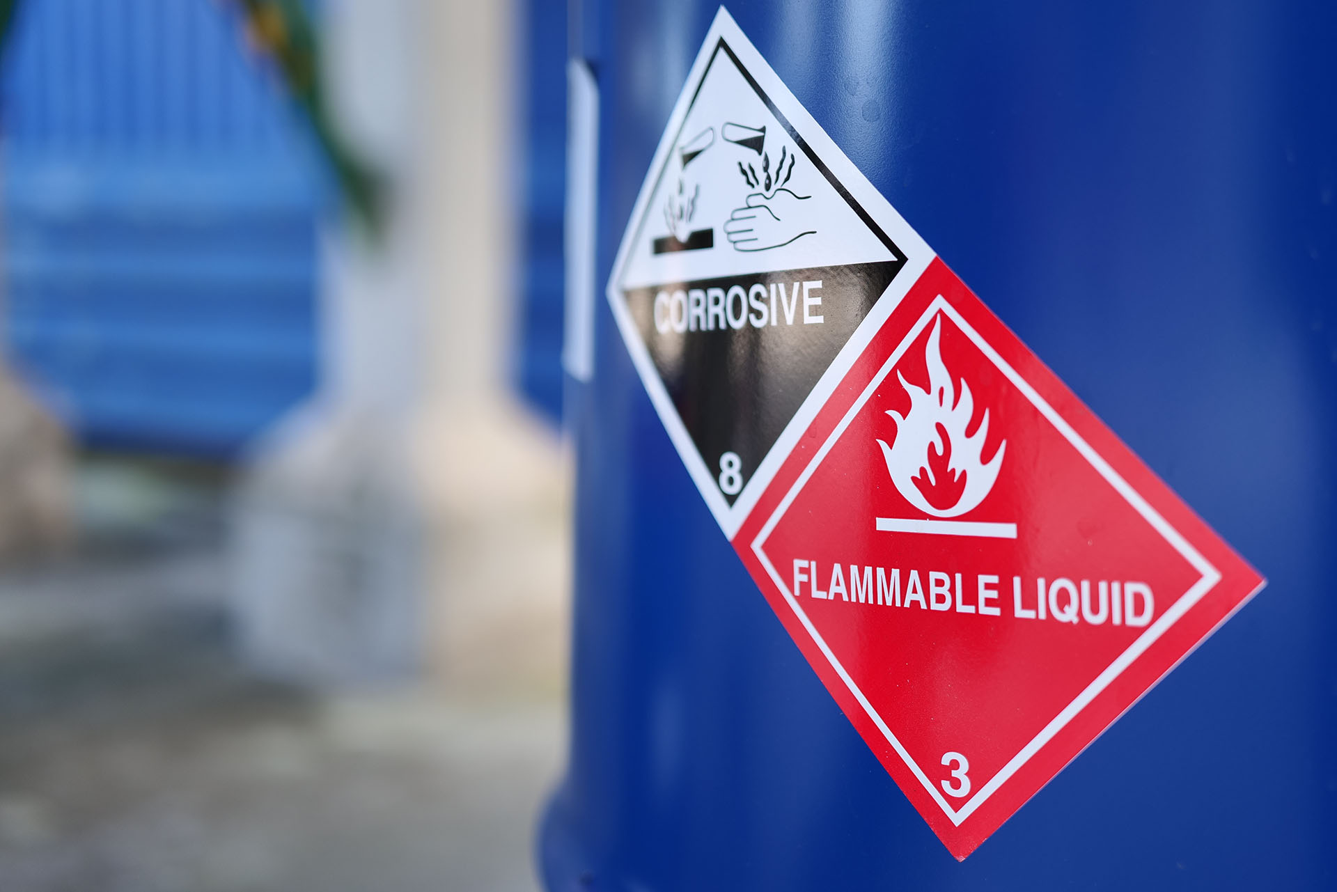 A blue barrel featuring clear warning labels for corrosive and flammable materials shows customers what hazardous items removal companies are unable to transport, helping you identify restricted materials.
