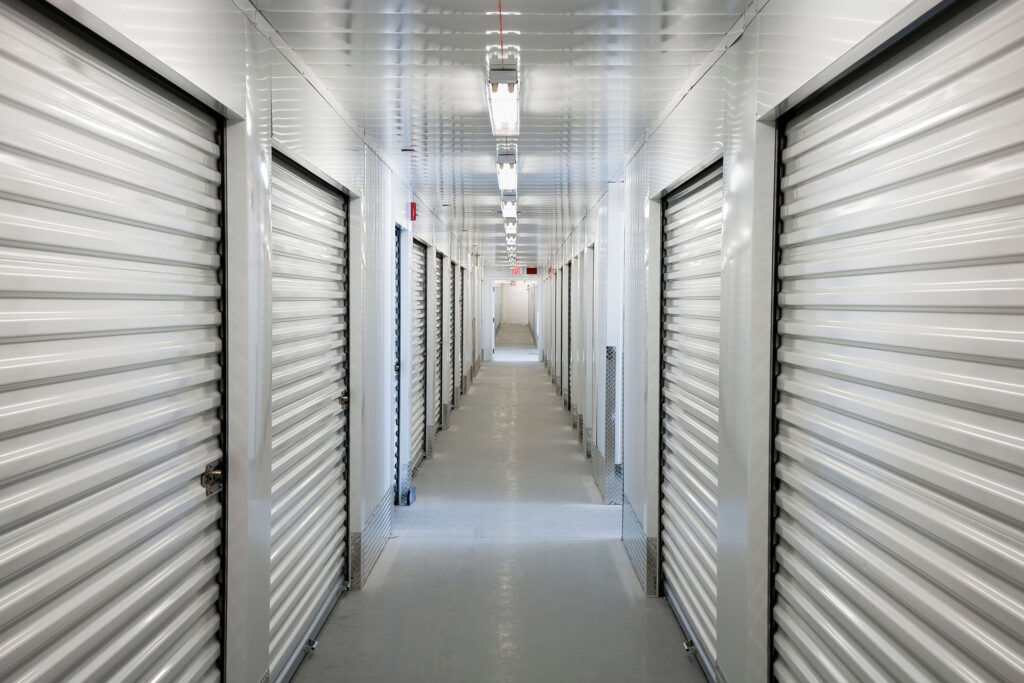 As you enter, you’ll find a brightly lit corridor in our storage facility. Closed metal roller doors are on both sides for your units, with fluorescent lighting above to help guide you safely through the space.