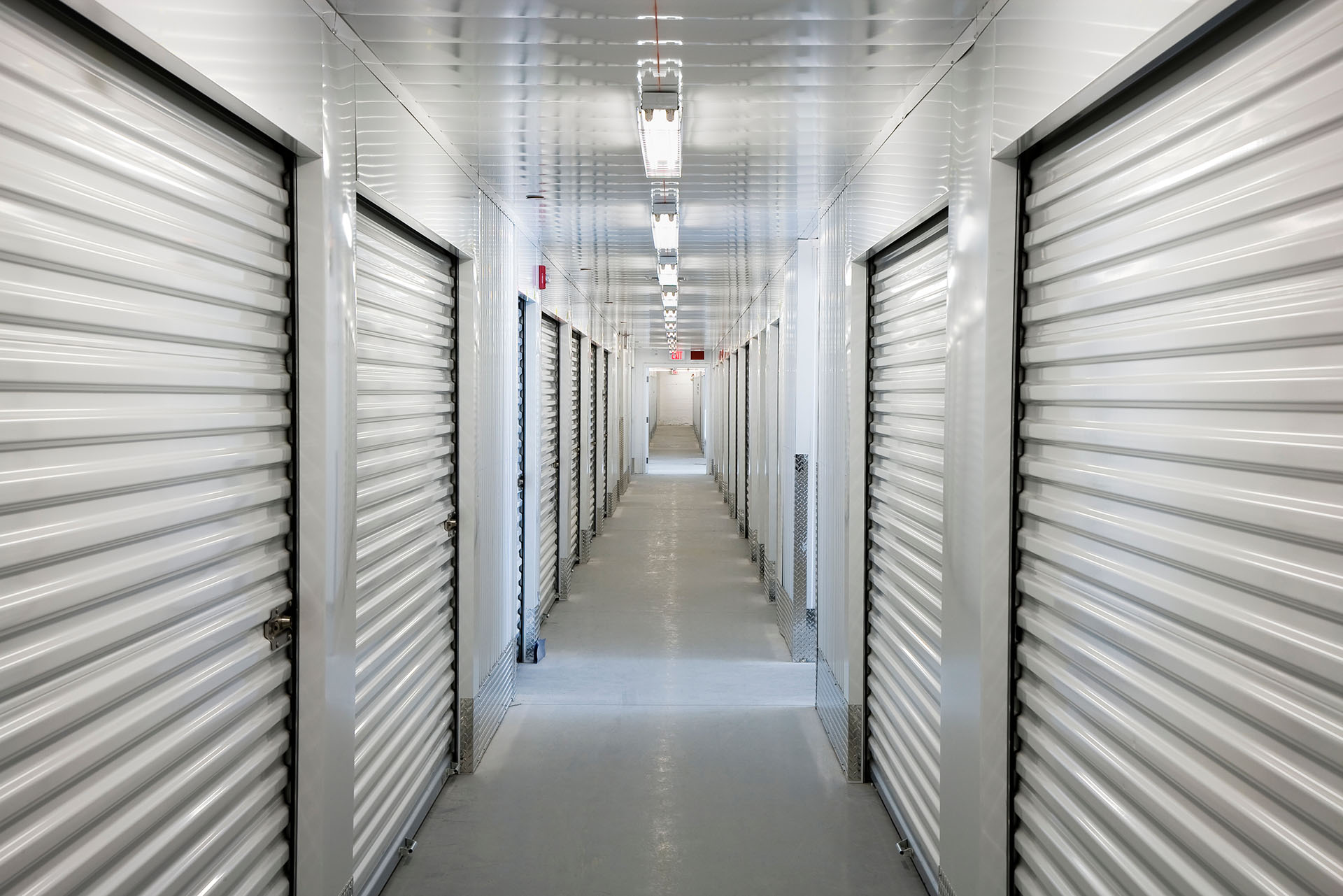 As you enter, you’ll find a brightly lit corridor in our storage facility. Closed metal roller doors are on both sides for your units, with fluorescent lighting above to help guide you safely through the space.